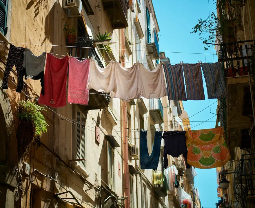 Du linge étendu sur des fils tendus d'une façade à l'autre, entre deux immeubles anciens d'une ruelle napolitaine