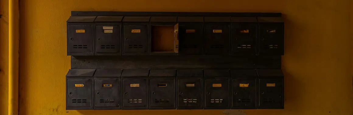 Boîtes aux lettres d'un immeuble alignées sur un mur ocre
